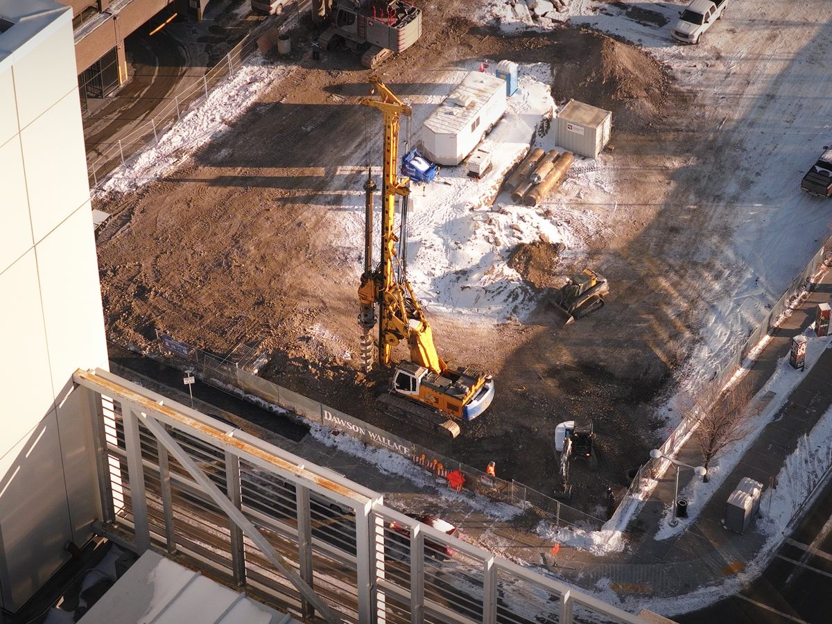 Aerial view of a Calgary construction site with a drill rig and site trailers