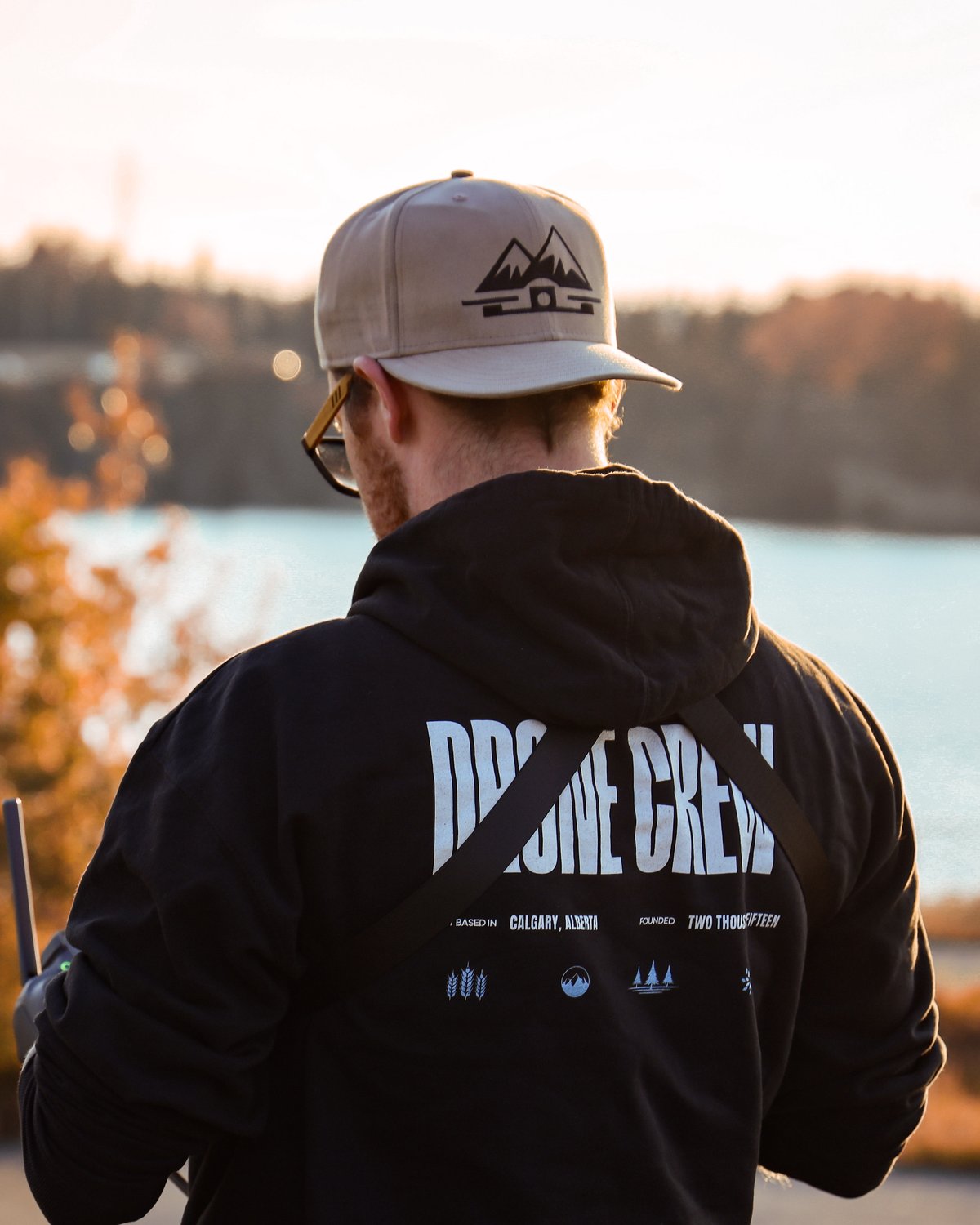 Peak FPV drone pilot on location in Calgary wearing a Drone Crew jacket, controller in hand